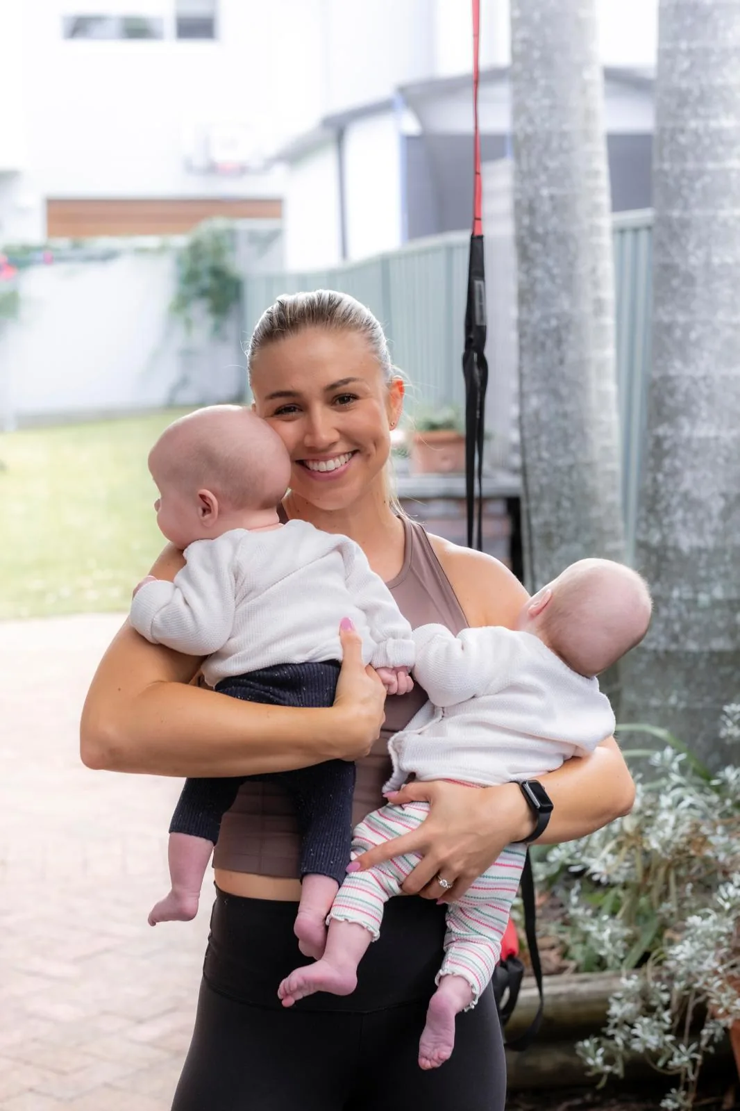 Tayla smiling warmly while holding two babies in her arms