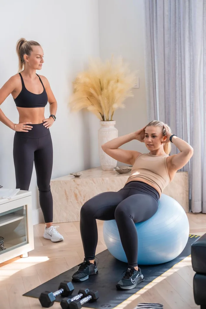 A client performing seated exercises on a stability ball while Tayla observes in the private studio